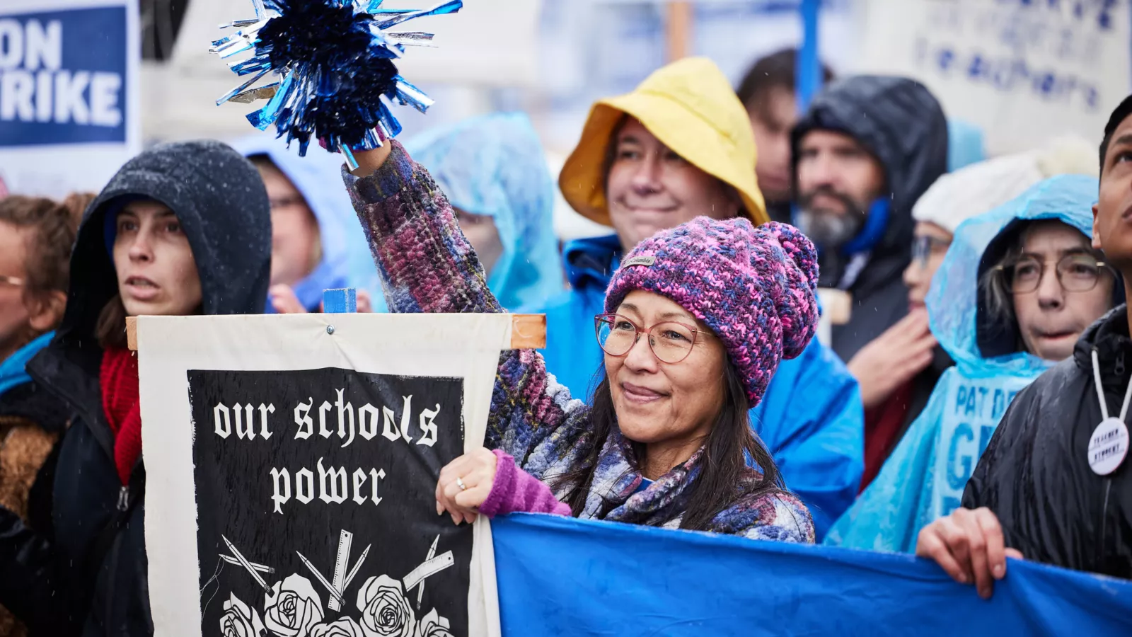 crowd at a rally during the PAT 2023 strike; camera is focused on a member of the crowd with a sign that reads 'our schools power'