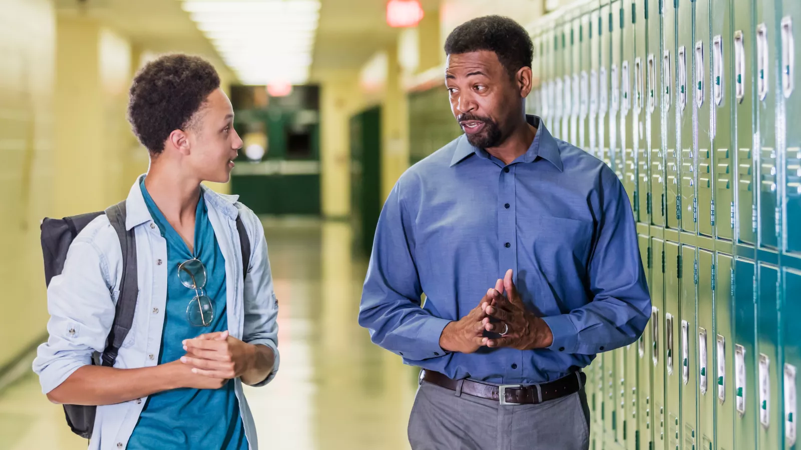 Teacher and student talking in school hallway