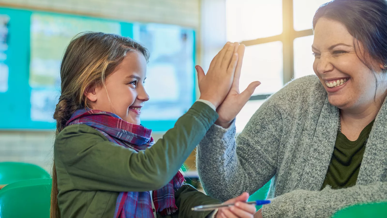 Elementary school girl high-fiving her teacher in class