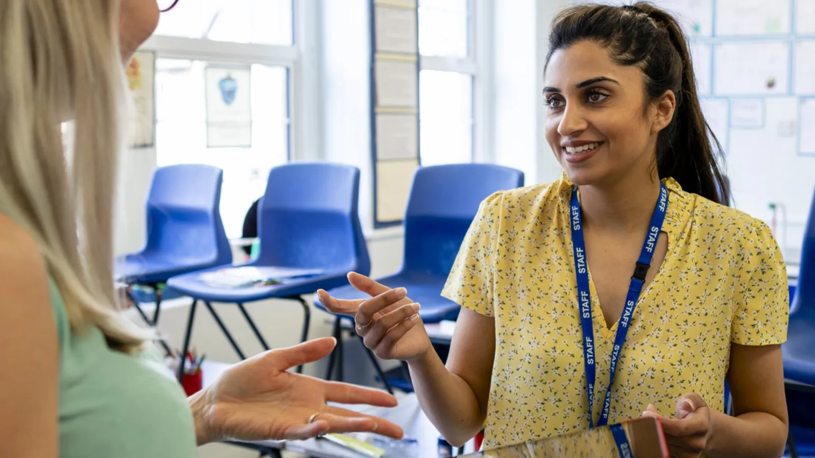 Educators stand in classroom talking over an iPad