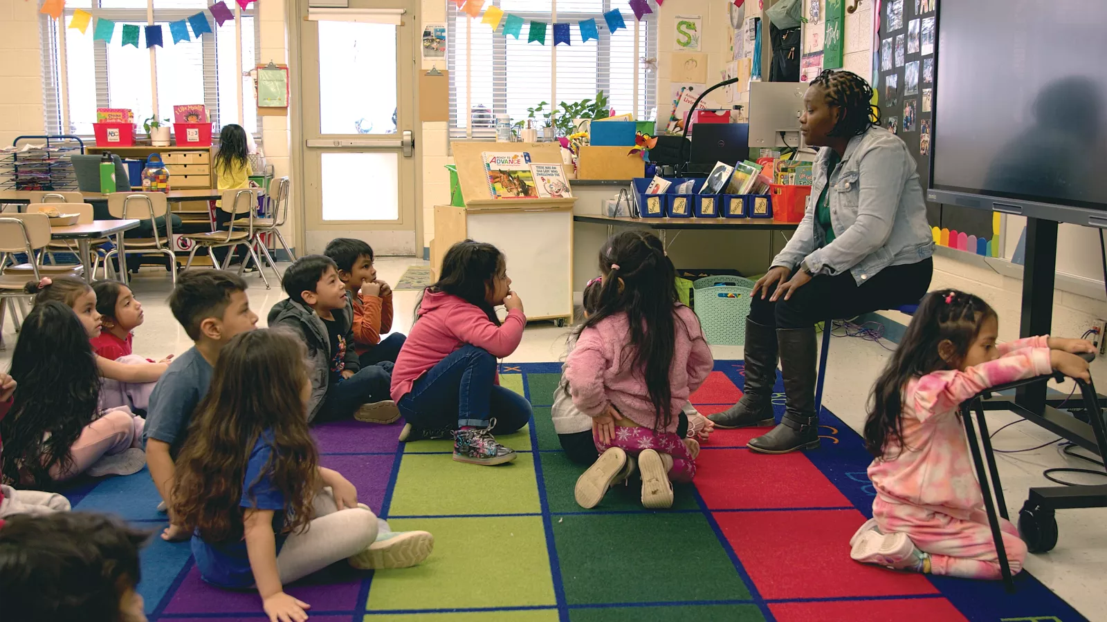 Deneshia Smith sits in front of seated preschool students and tells stories as the children sit quietly and listen.