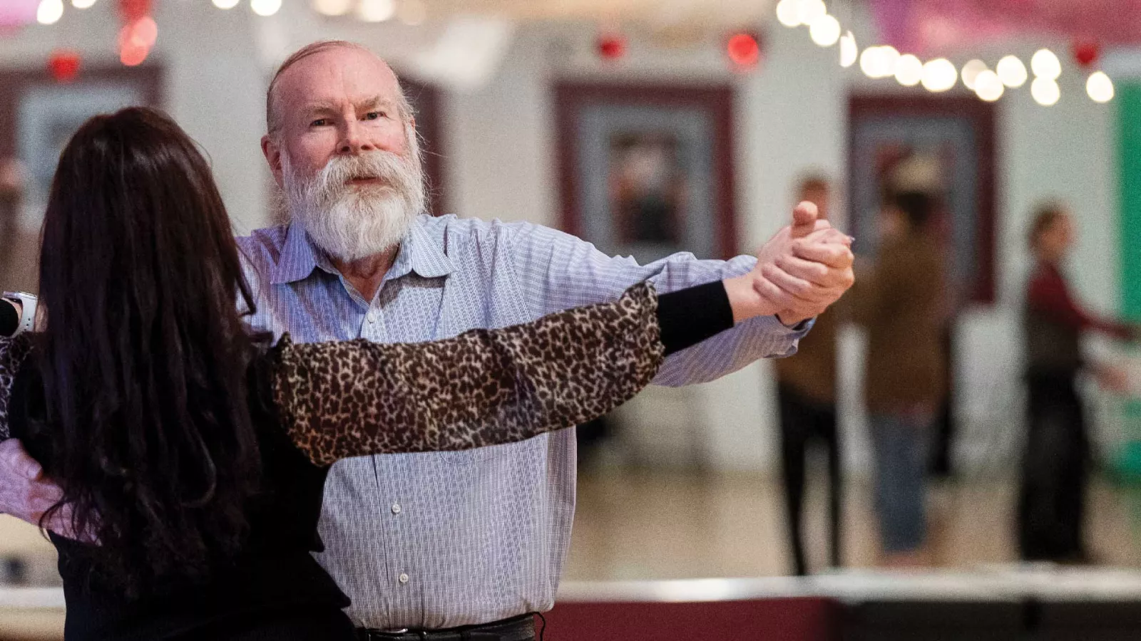 Mike Ragan dancing the tango with his partner in a dance studio with a mirror in the background.