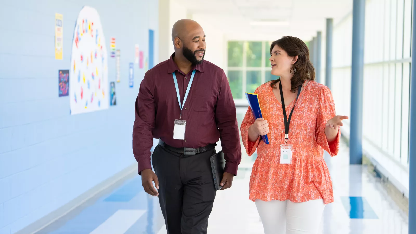 two educators walk down a school hallway