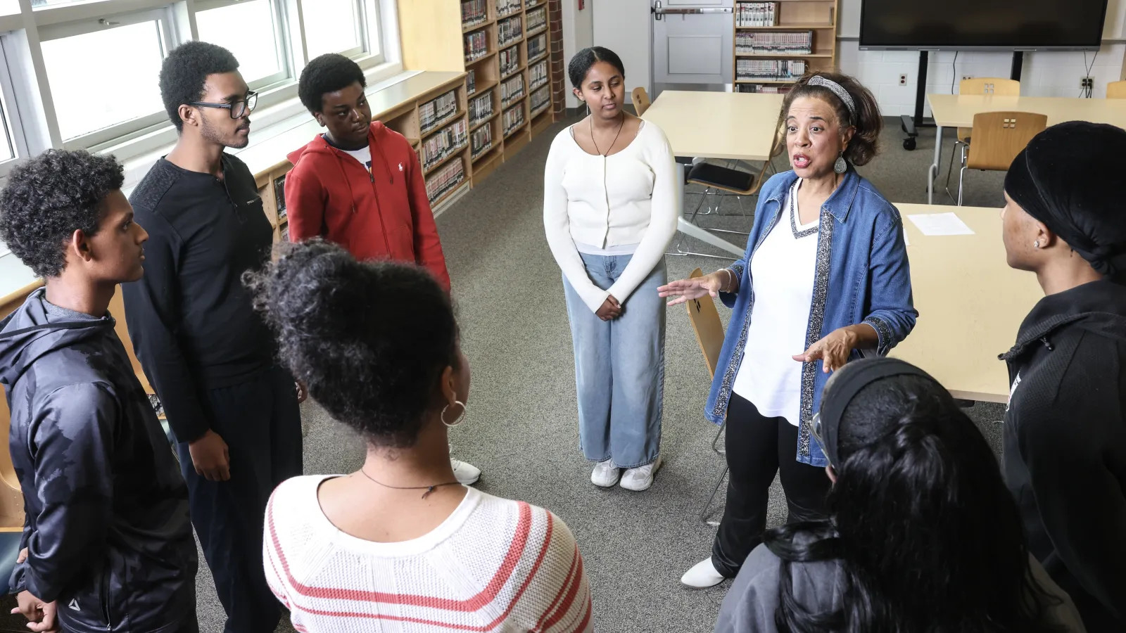 Teacher surrounded by students in school library