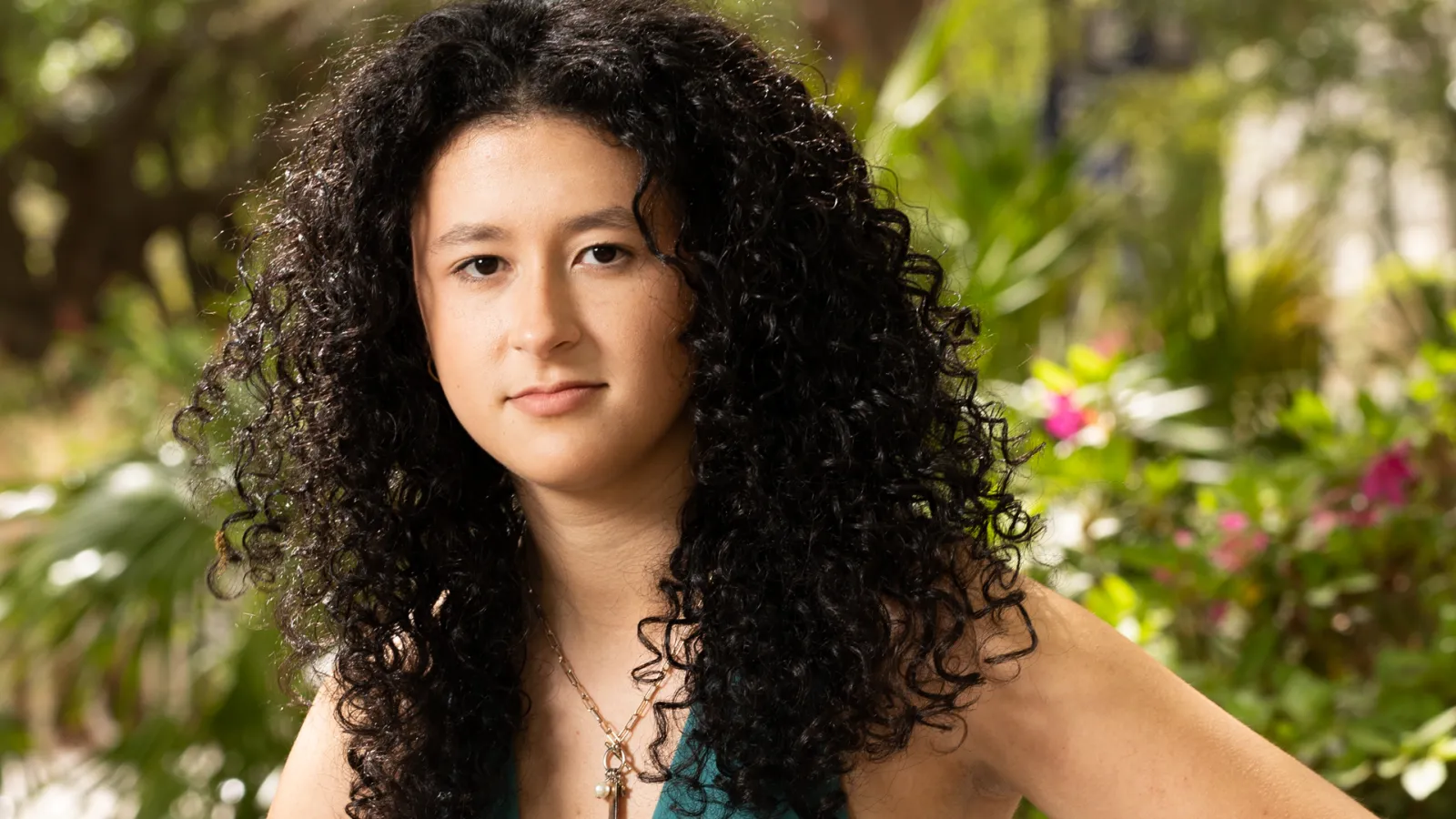 A woman sitting on a bench in a park, looking thoughtfully into the camera.