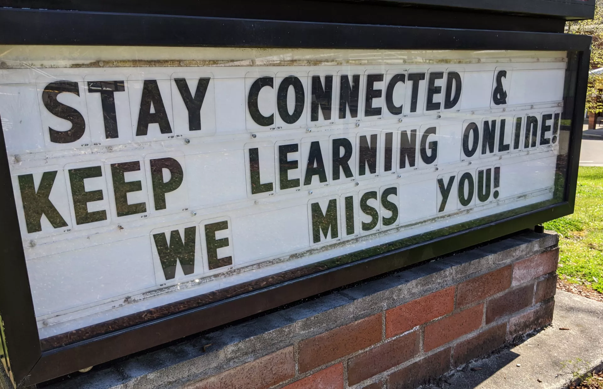 A school sign encourages students to stay connected and learn online