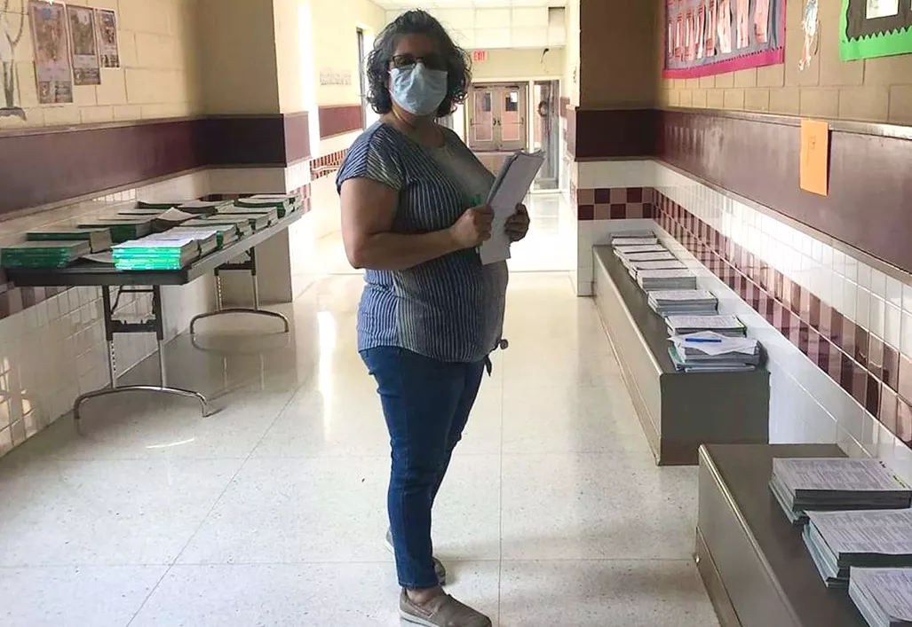 A teacher prepares packets for students returning to school during COVID-19