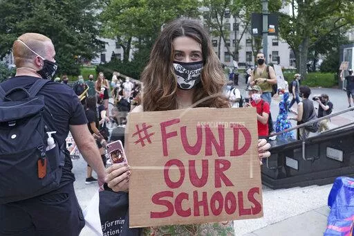 woman with sign that says hashtag fund our schools