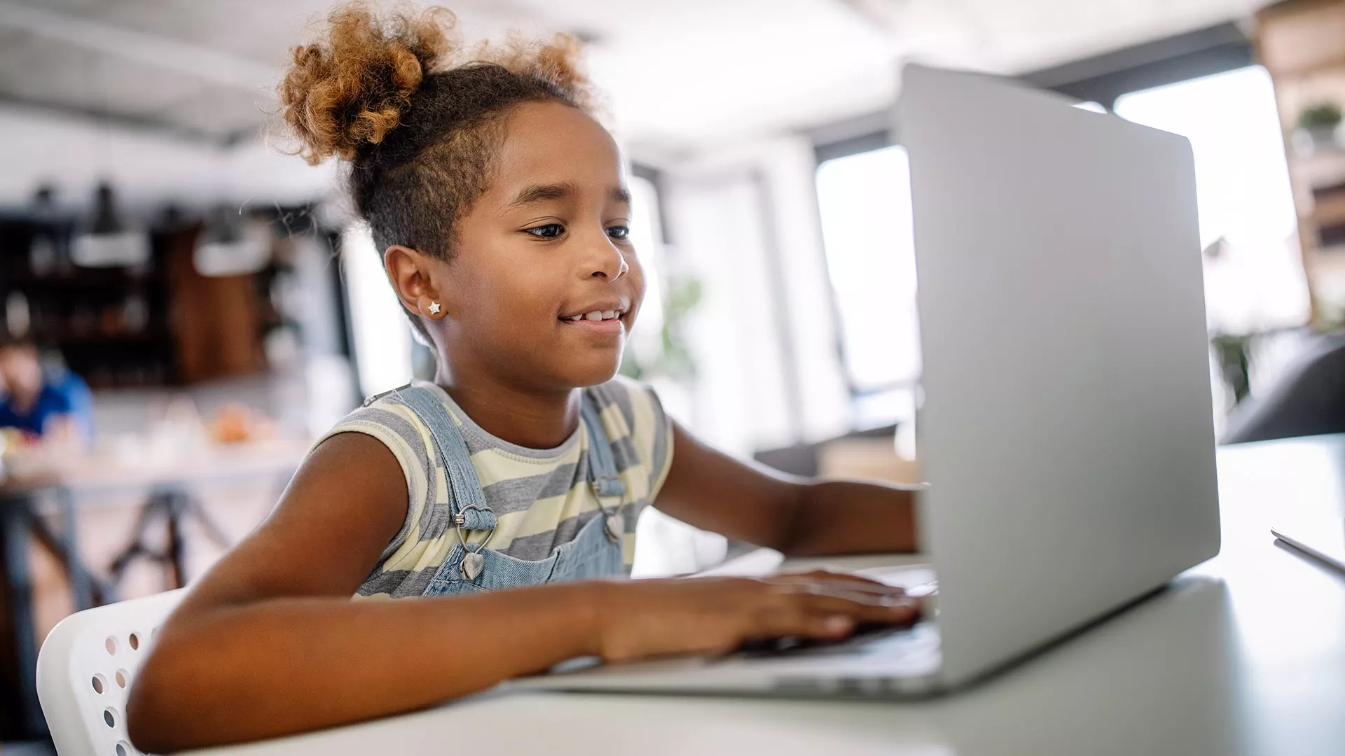 An African American girl uses a laptop