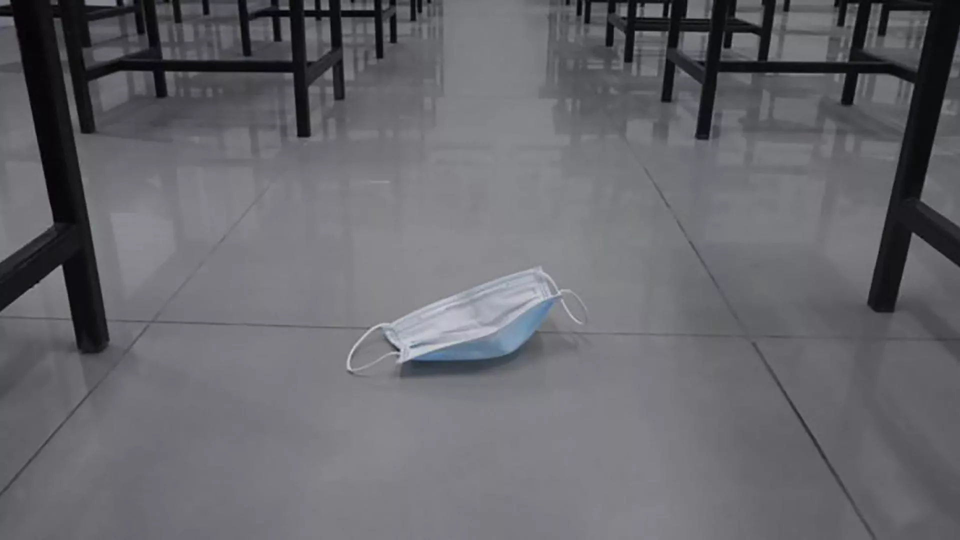 A mask lies discarded on a classroom floor