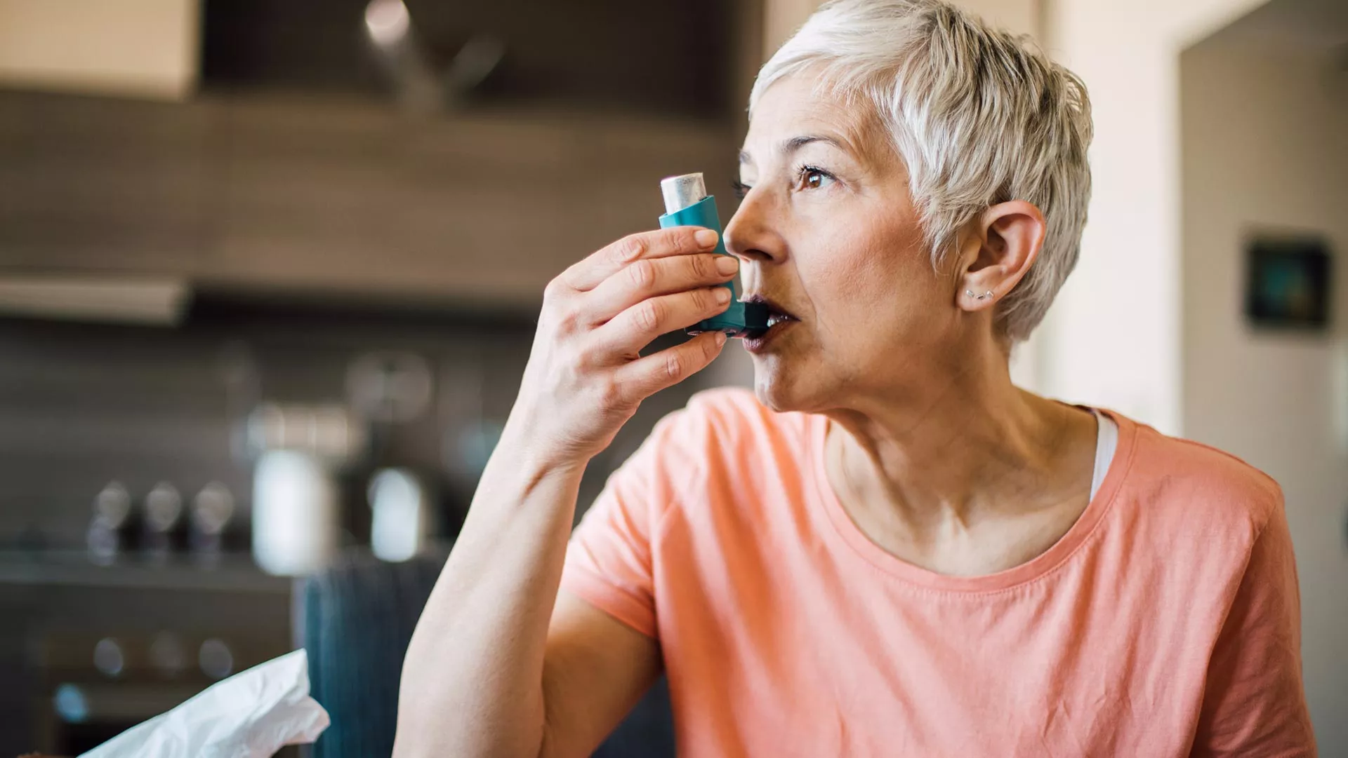 A middle-aged woman uses an asthma inhaler