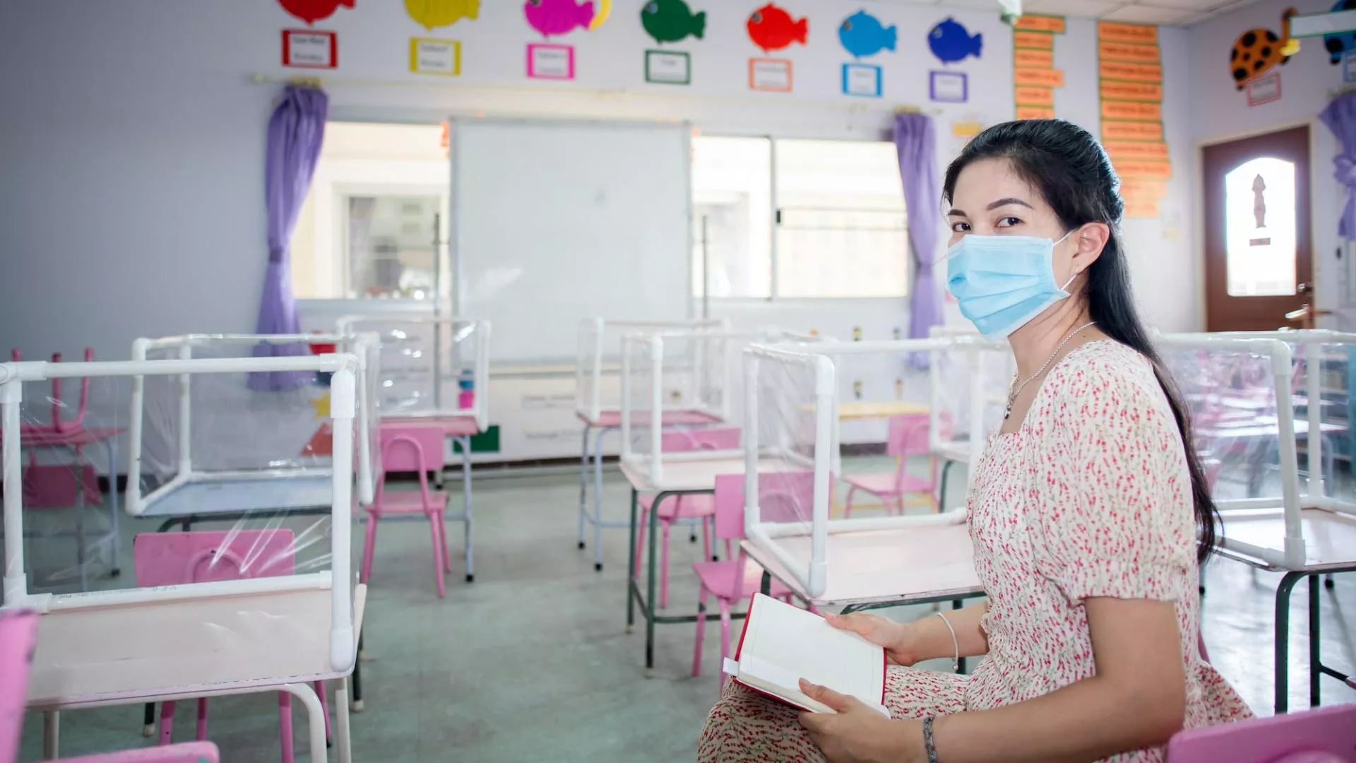 A teacher wears a mask in a socially distanced classroom
