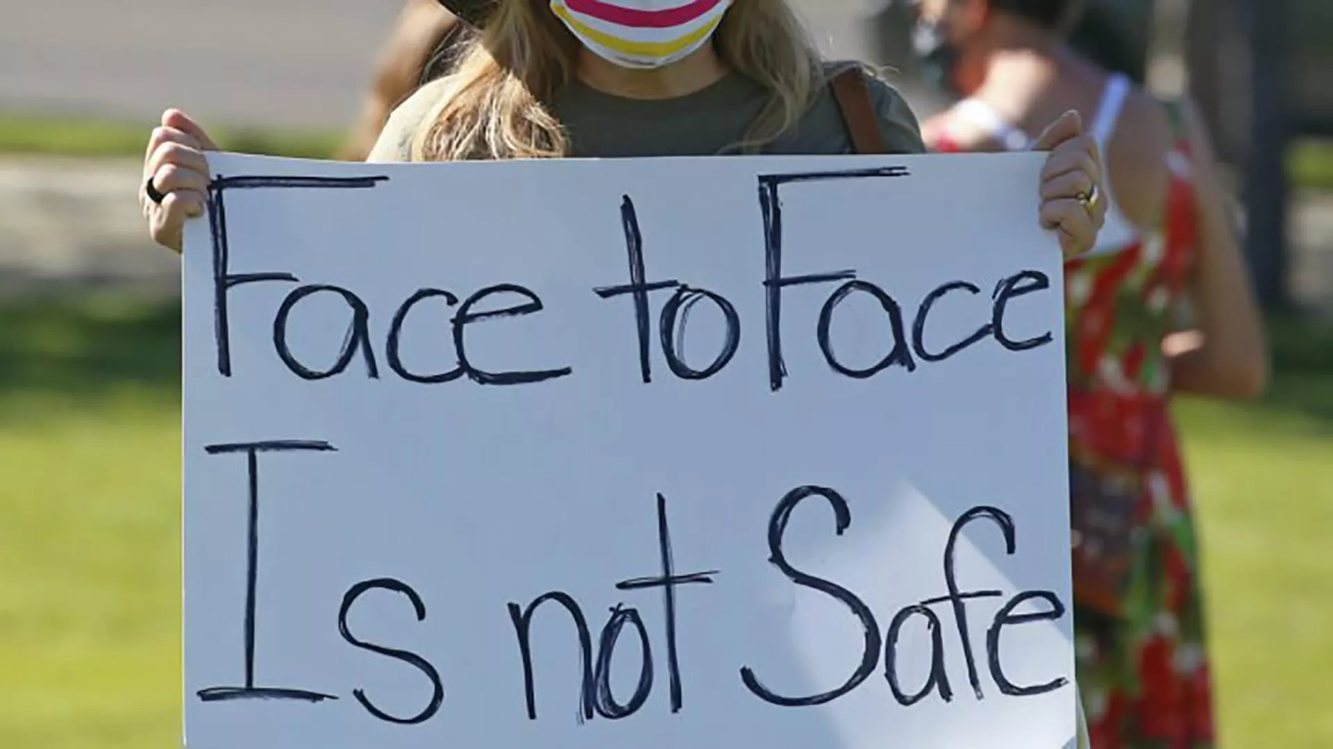 parents hold signs protesting school openings