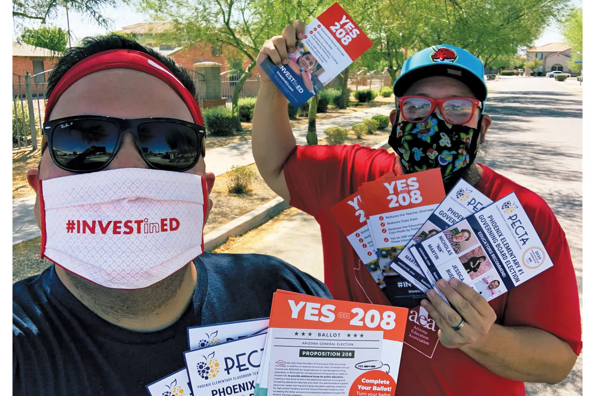 Jay Barbuto, with a fellow activist, wears a mask that says "Invest in Ed" and carries pamphlets that say YES 208.