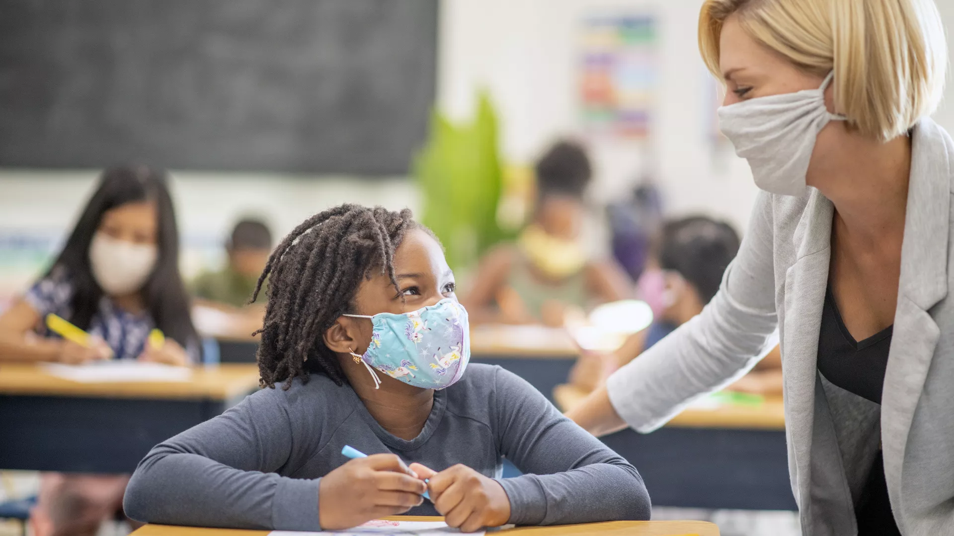 masked female student with masked teacher in classroom