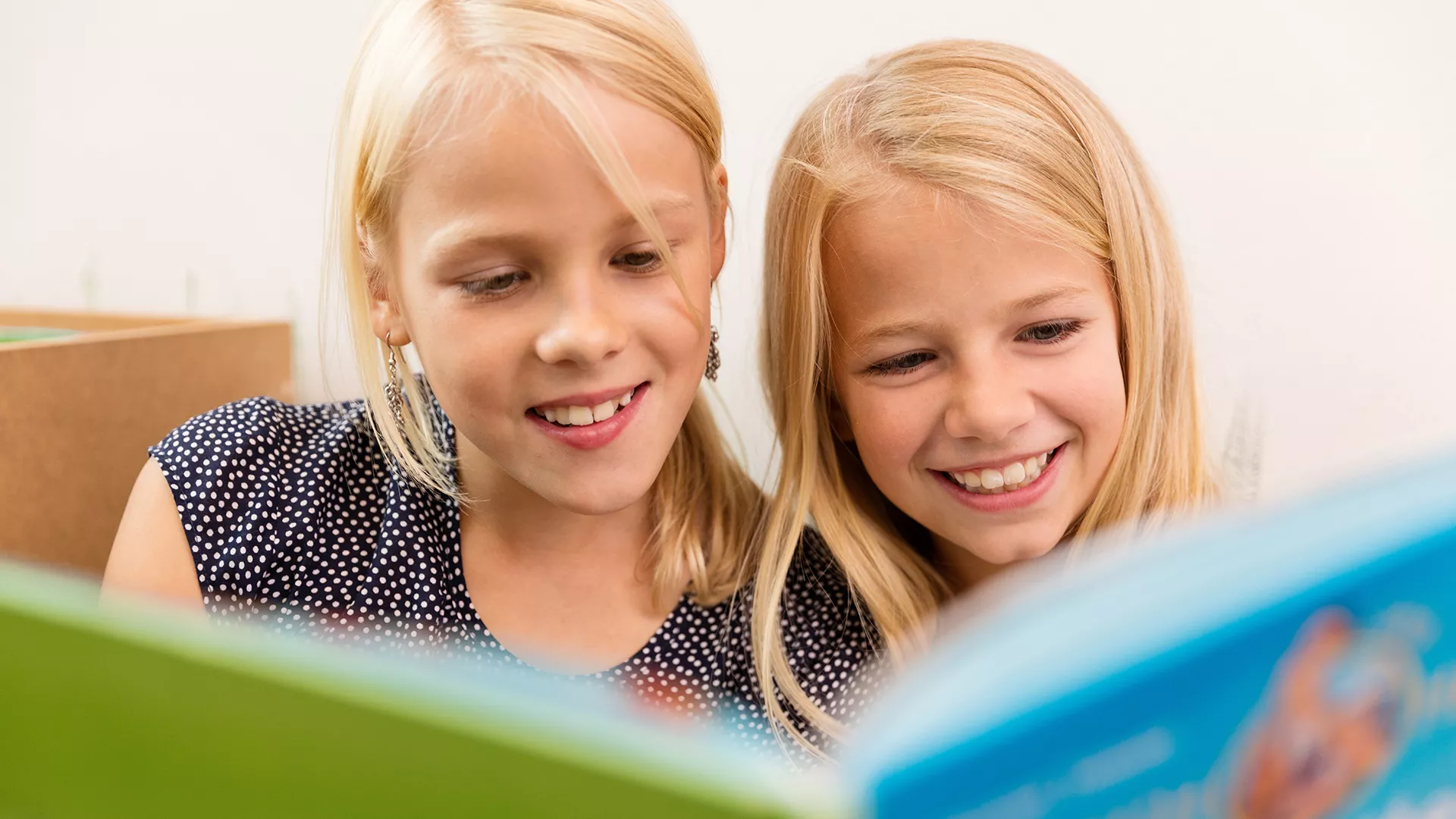 two young girls reading a picture book together