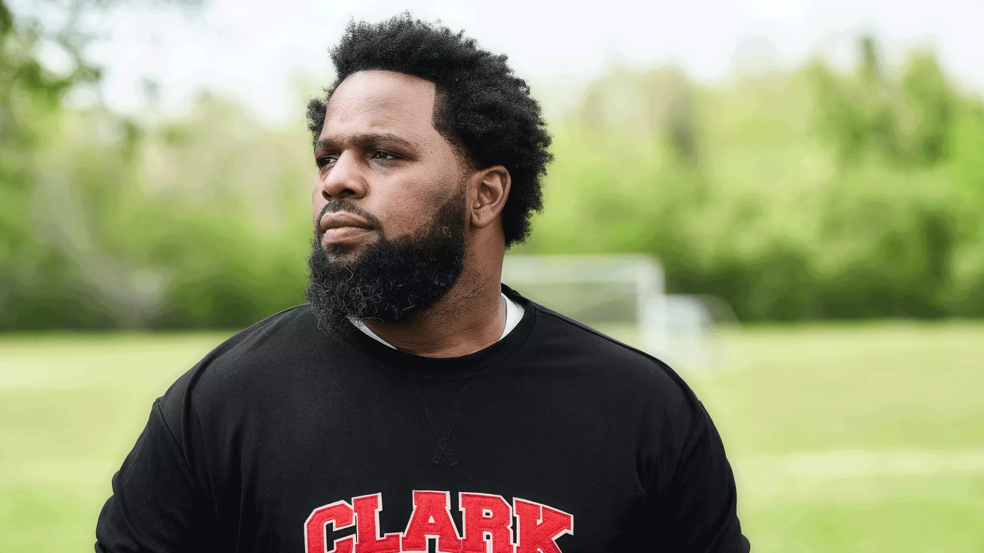 D. Cook standing in front of a soccer field in a black shirt.