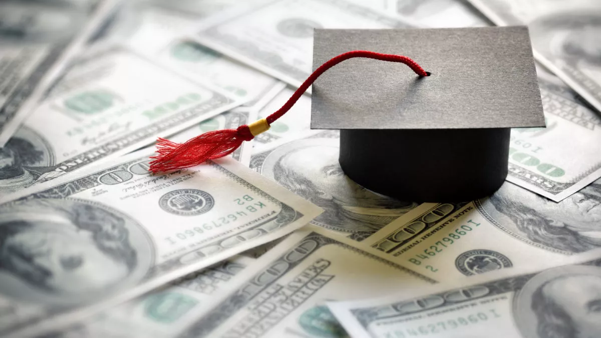 A mortarboard rests on a pile of money