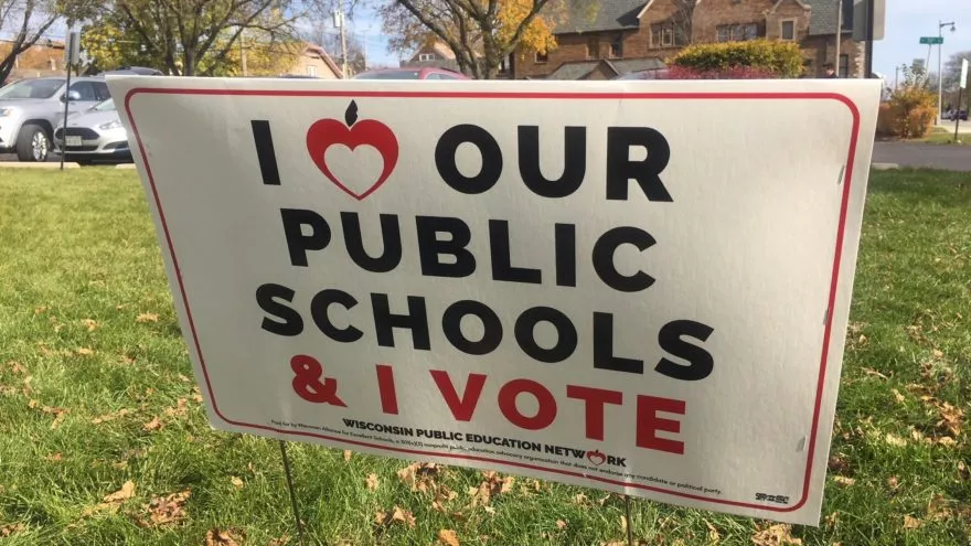 A sign reads "I heart public schools and I vote"