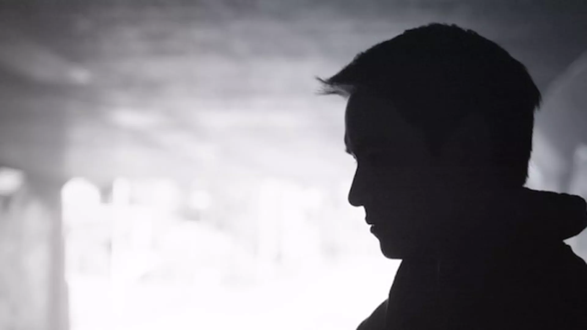 black and white image of a student in profile in a blurred school hallway