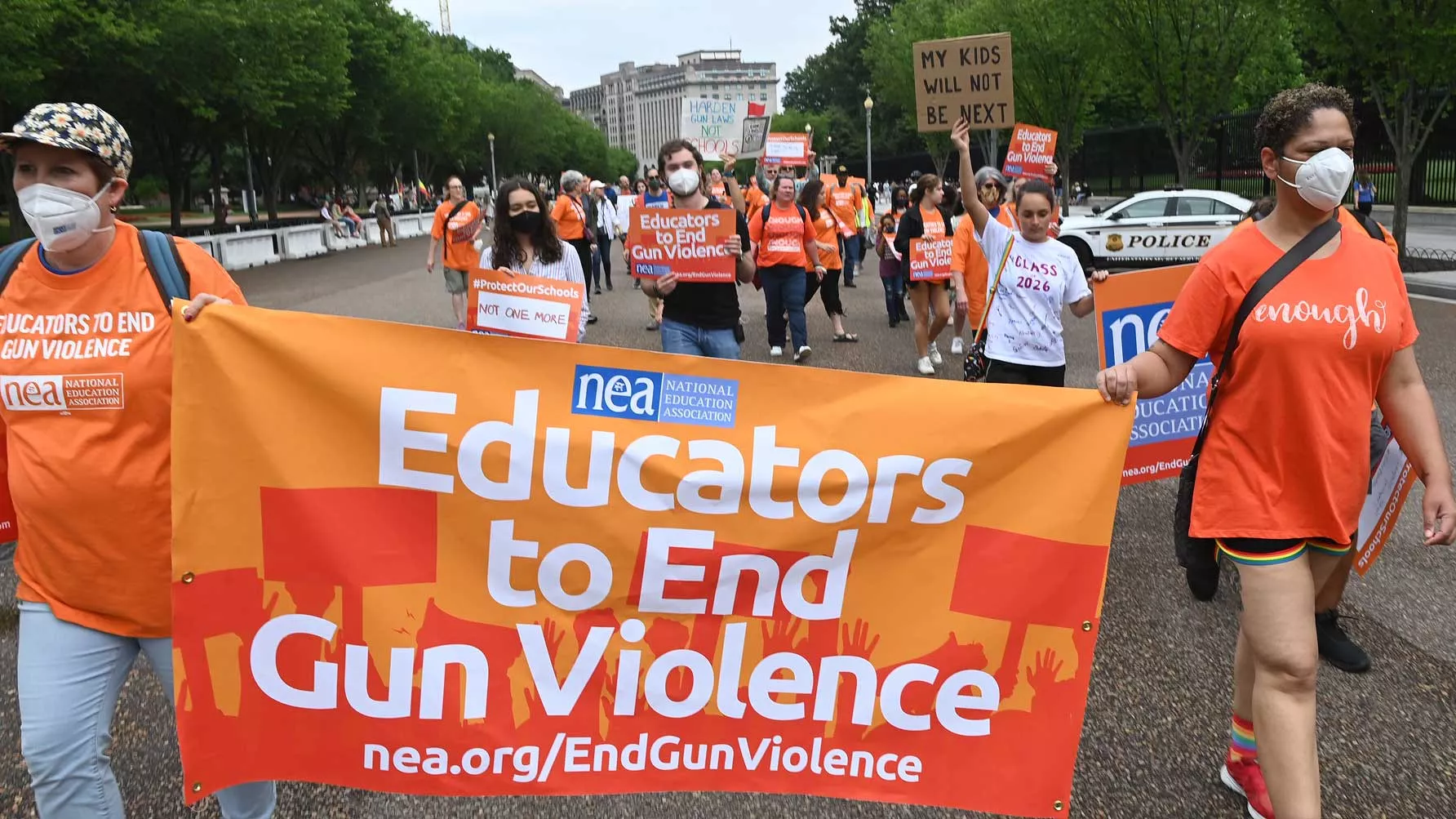 Educators march with a banner that says "Educators to end gun violence"