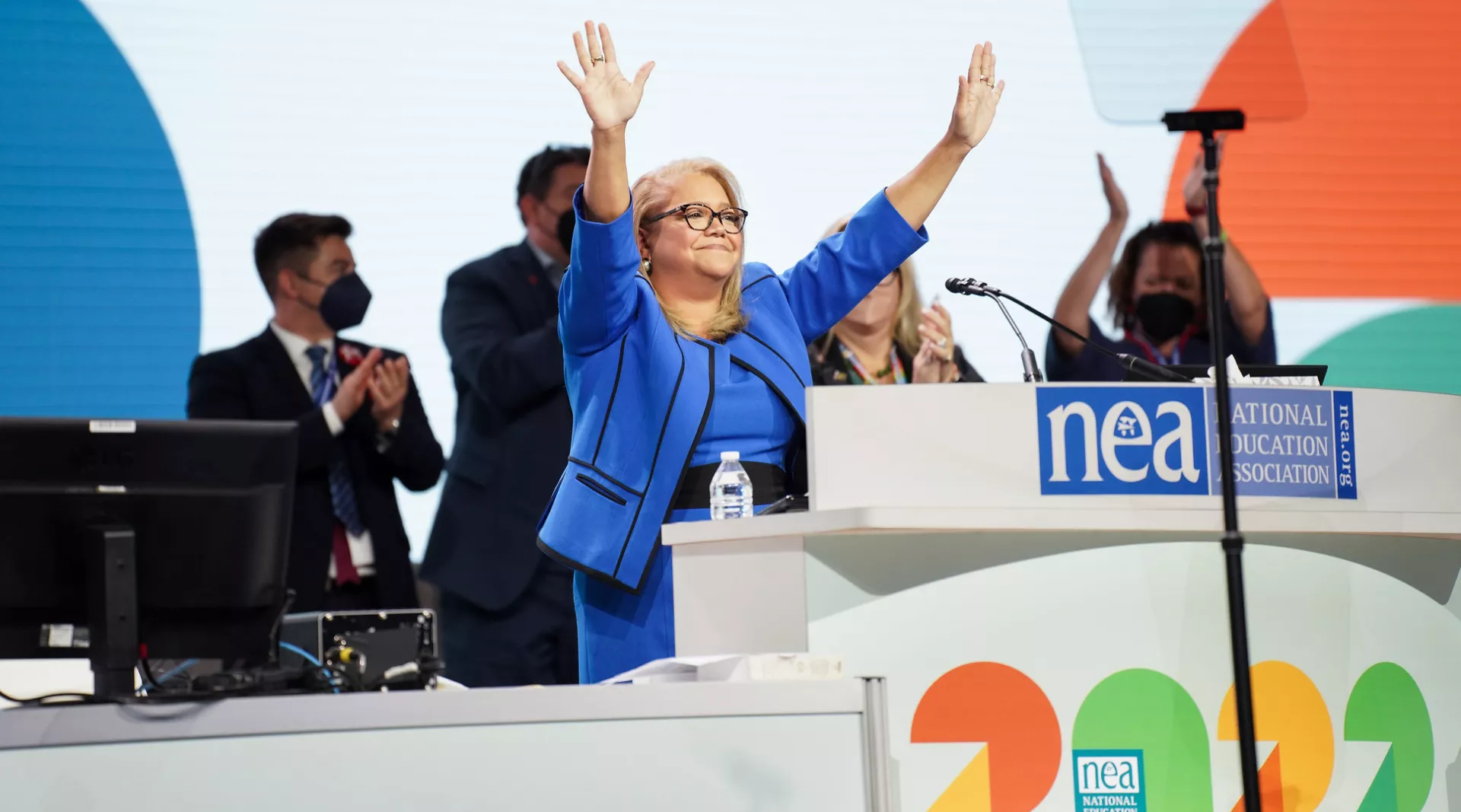 NEA Executive Director on event stage, hands raised