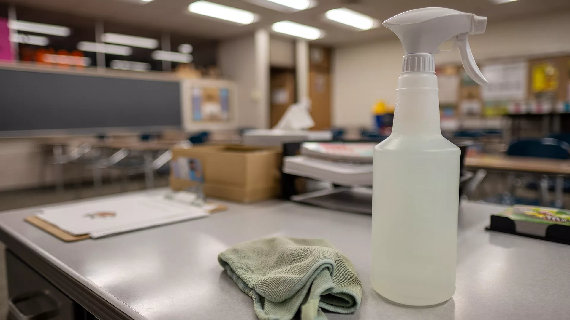 spray bottle and cleaning cloth on school desk