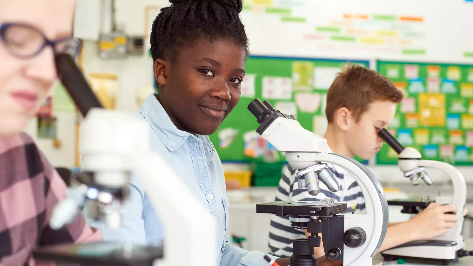 High School girl looking through microscope