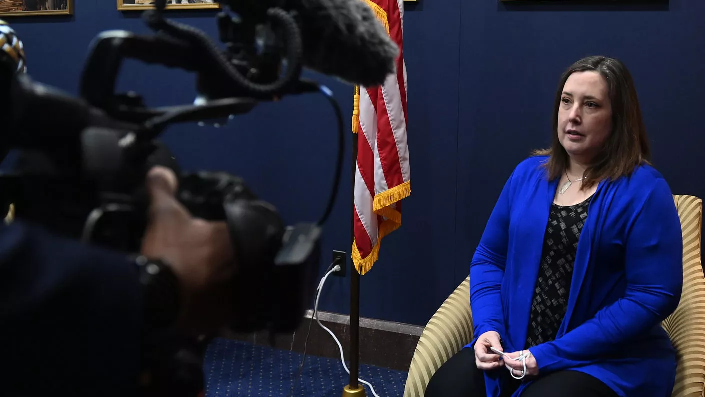 A woman in a blue jacket in front of a camera