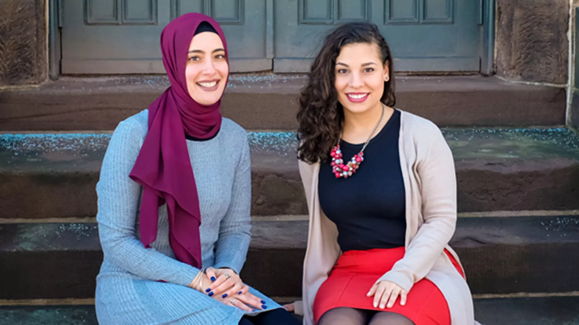 Educators Nagla Bedir and Luma Hasan sit on stairs outside