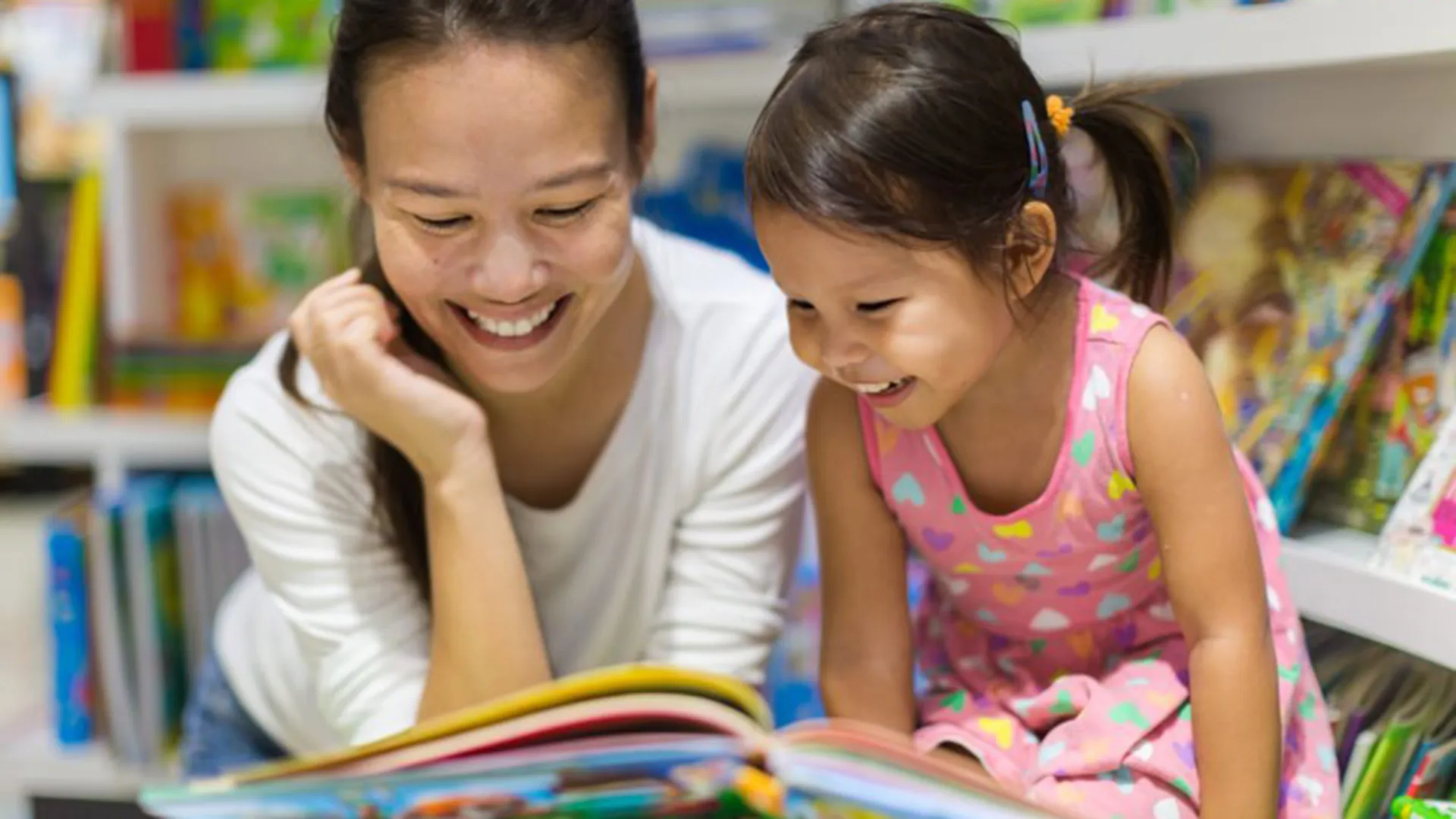 Asian mother and daughter reading a picture book together