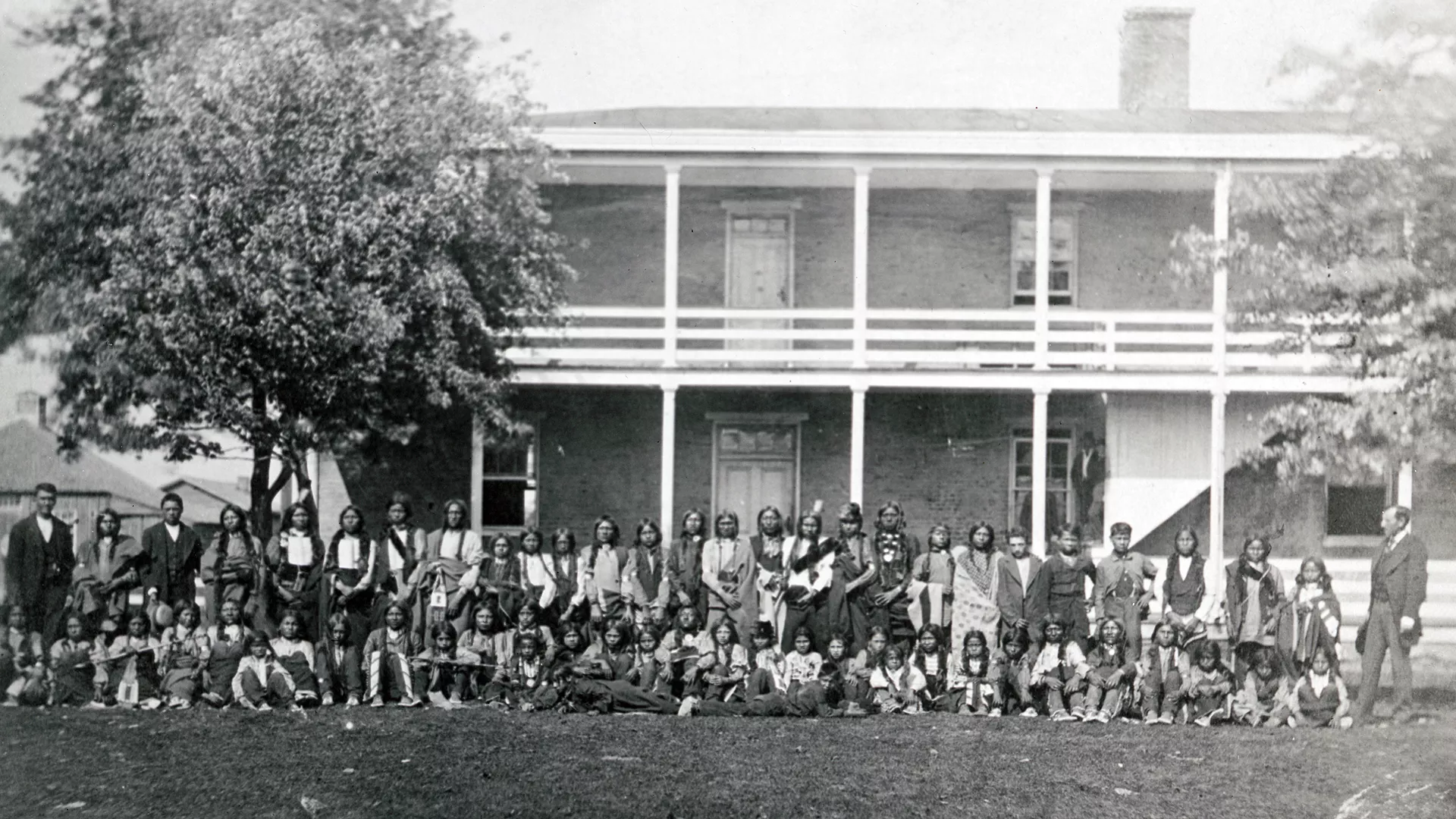 Sioux Boys standing and seated for a group photo in front of Carlisle Training School sometime between 1876-96