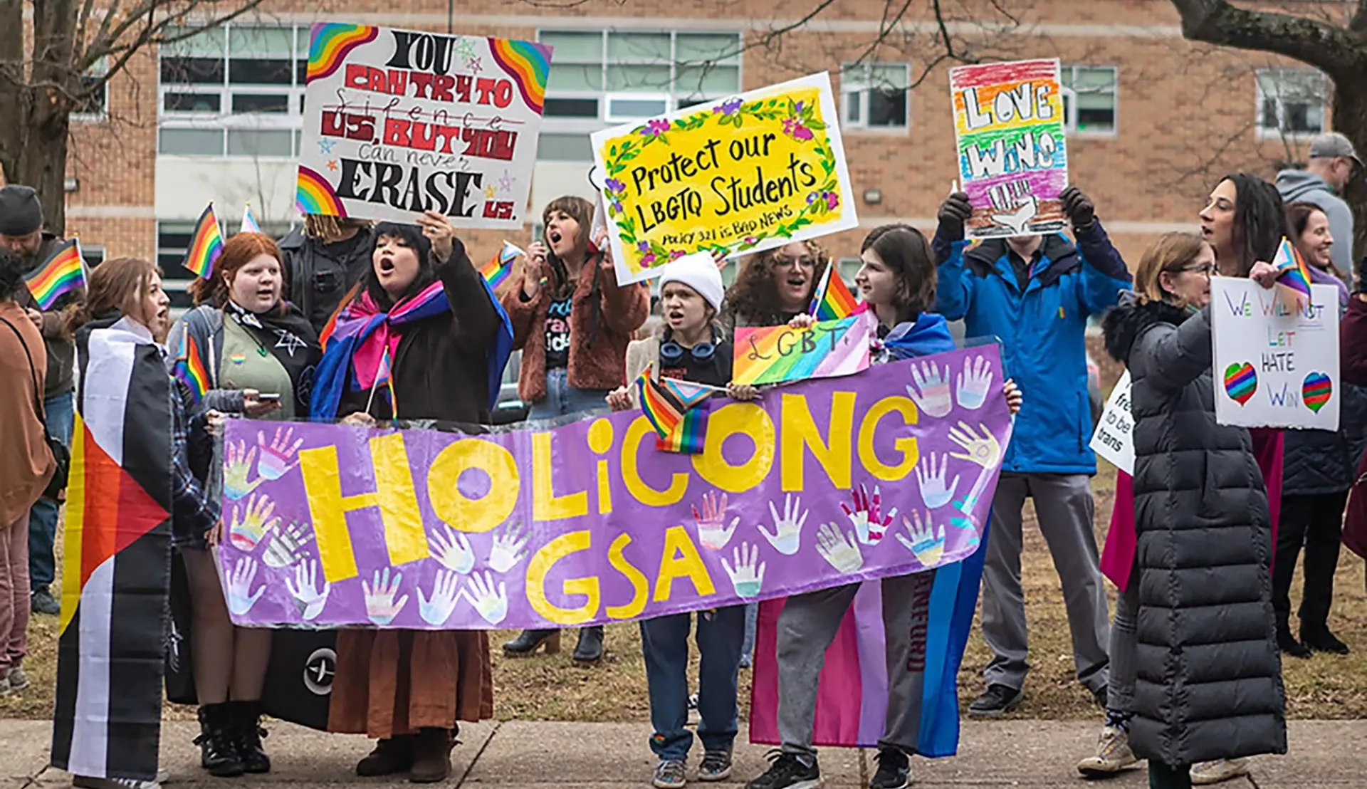 GSA student members hold signs and protest in front of their school