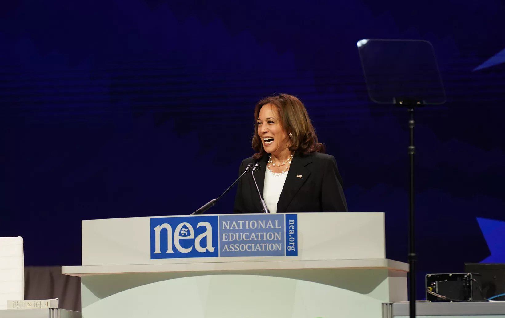 Kamala Harris standing behind NEA logo podium