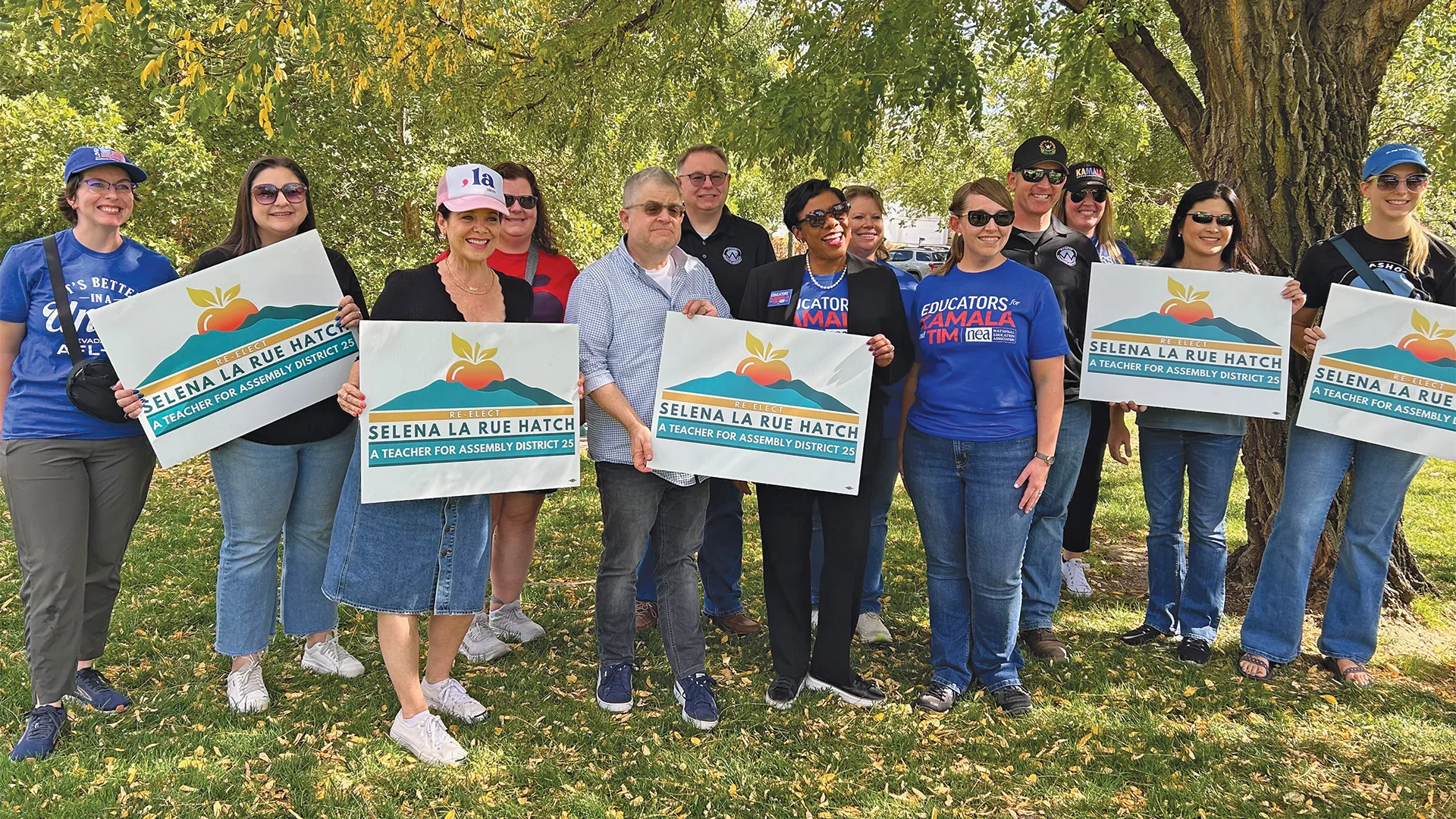 10 Nevada State Education Association members stand outside holding signs with NEA president Becky Pringle and Comedien Patton Oswalt