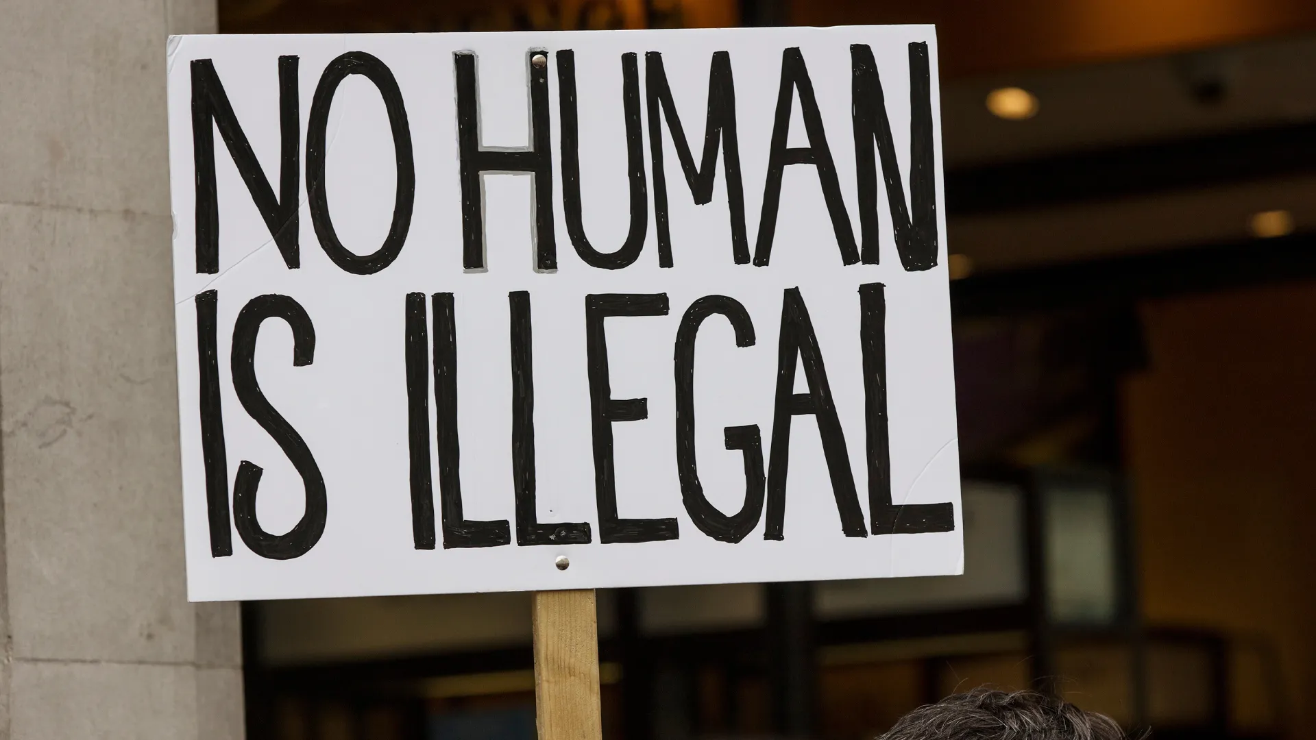 Rally sign that reads No Human is Illegal in black letters against a white background.