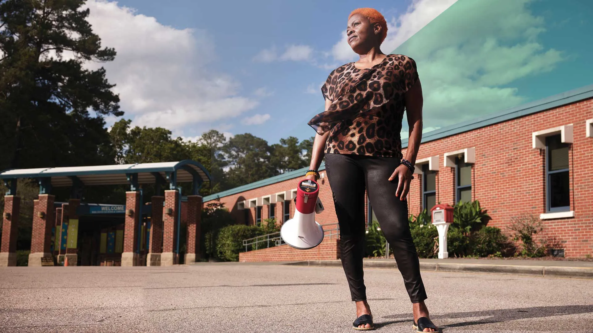 NCAE head custodian Patricia Crews outside of a school holding a bullhorn.