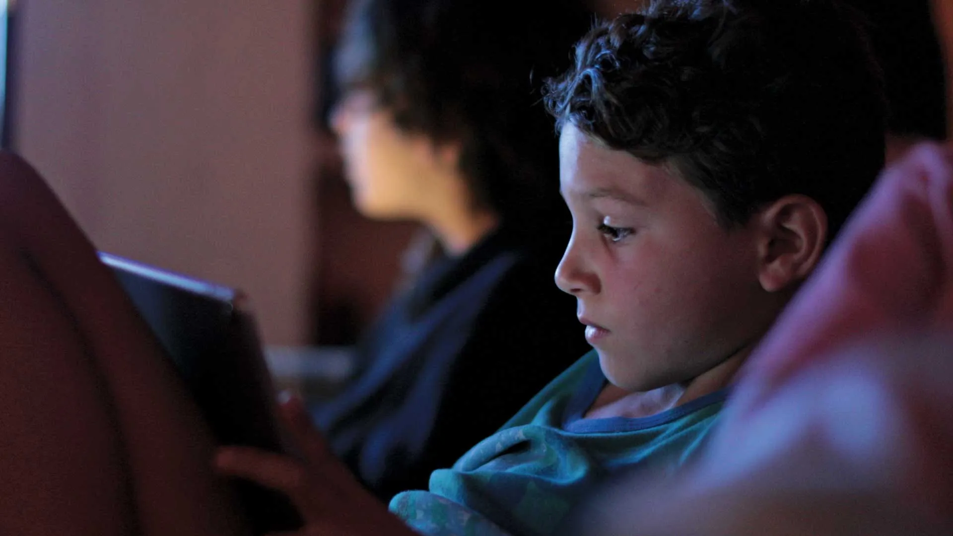 A boy looking at his electronic device.