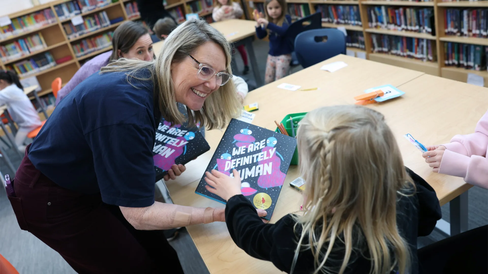 Media specialist shares a book with a young student in the school library
