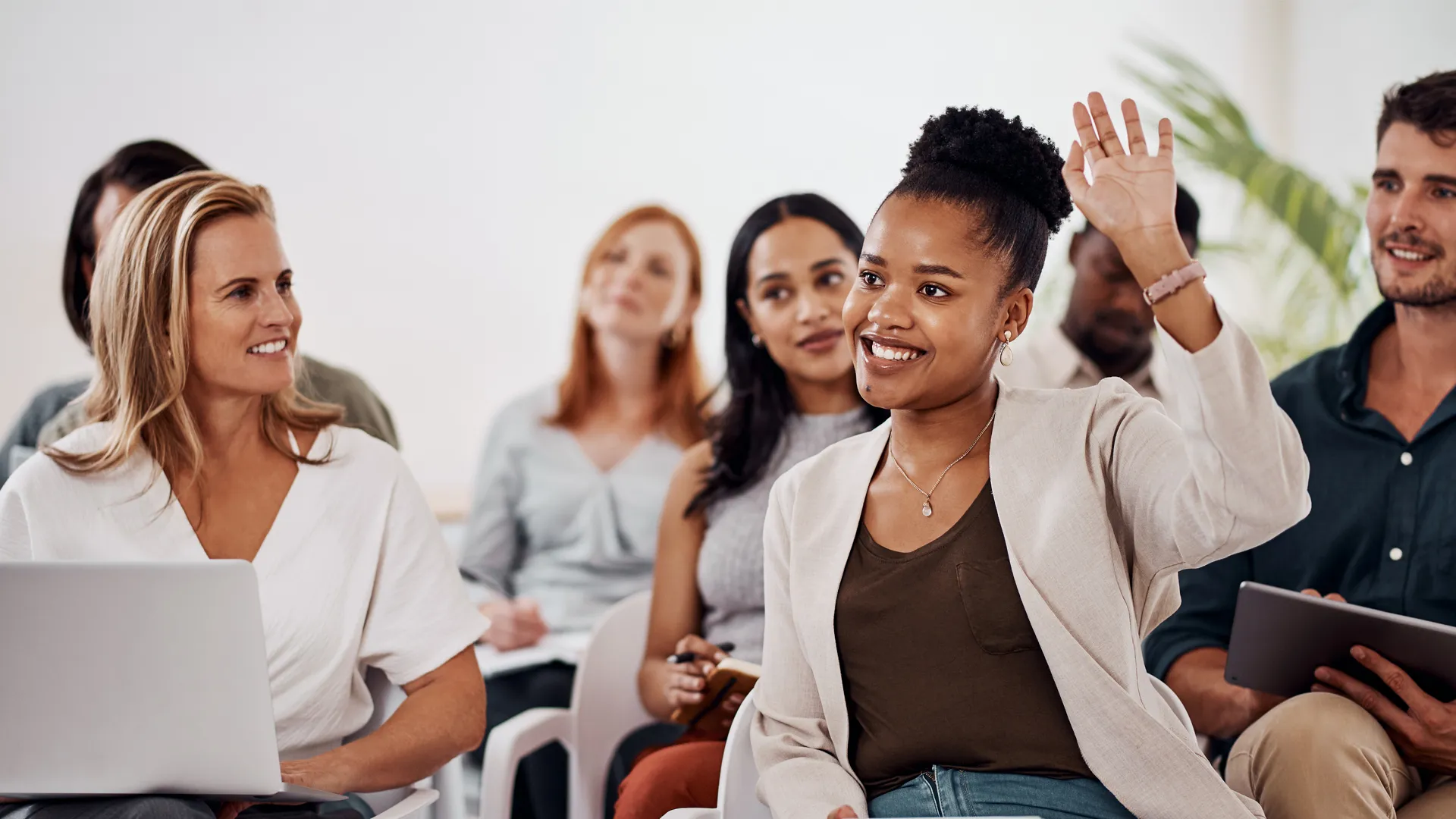 A woman raises her hand in a conference-room setting.