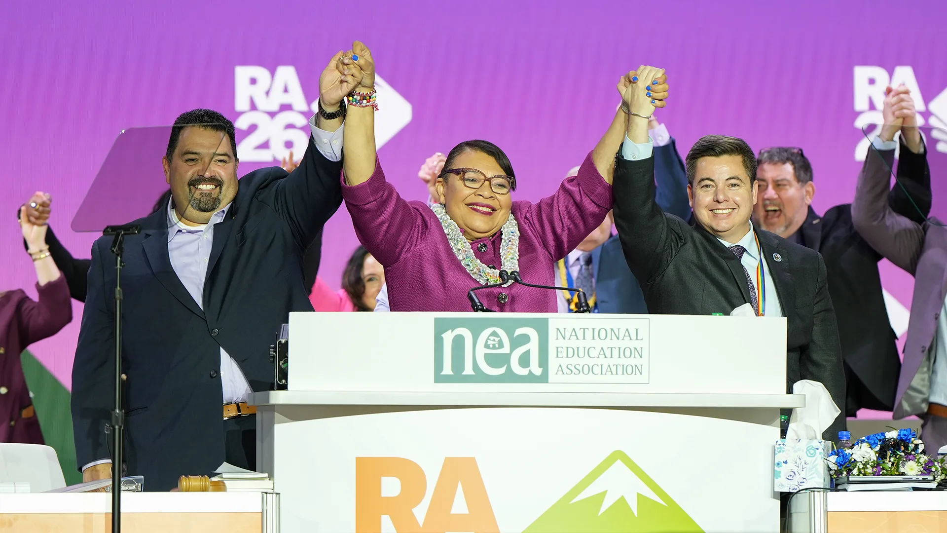 NEA's three officers stand with hands raised on RA stage