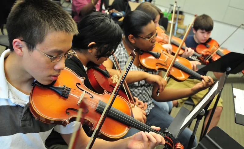 students play violins during a high school music class