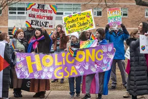 GSA student members hold signs and protest in front of their school