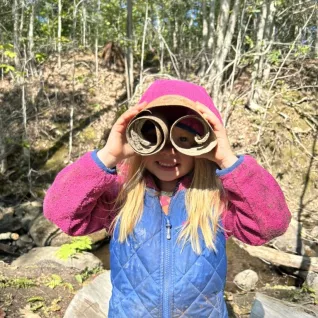 Photo of girl with binoculars up to her eyes