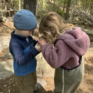 Photo of two children examining something in woods