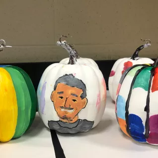 A pumpkin painted with the caricature of an adult male teacher.