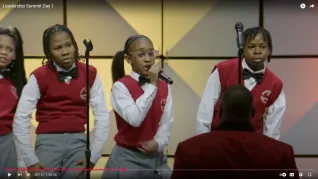 Students in uniform singing on stage