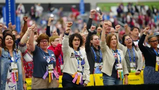 NEA RA delegates stand with fists raised to show solidarity with their international colleagues