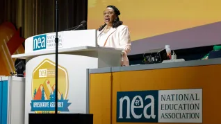 NEA President Becky Pringle stands at a lecturn to address NEA delegates