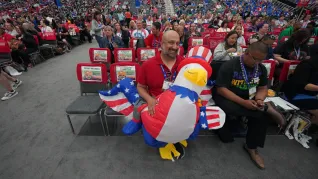 A male NEA delegate poses with an inflatable bald eagle in USA attire for the 4th of July